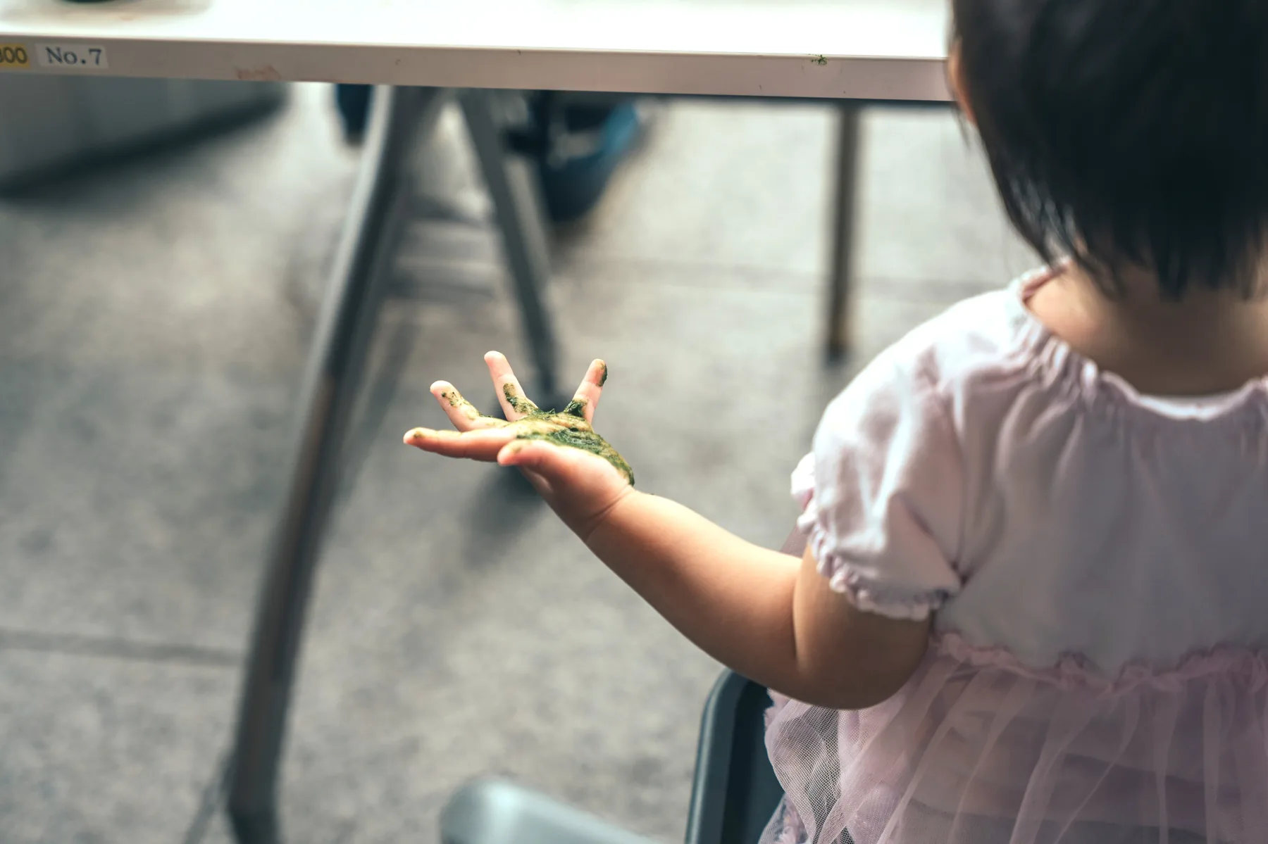 緑の染料の手形を見せる子ども